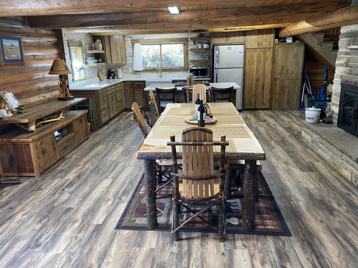 Open-concept cabin dining and kitchen with log beams