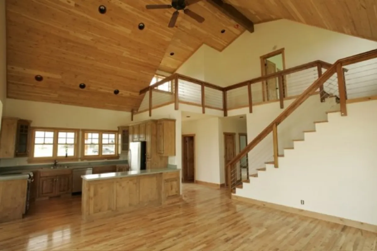 Open-concept living room with vaulted wood ceiling, staircase, and custom cabinetry