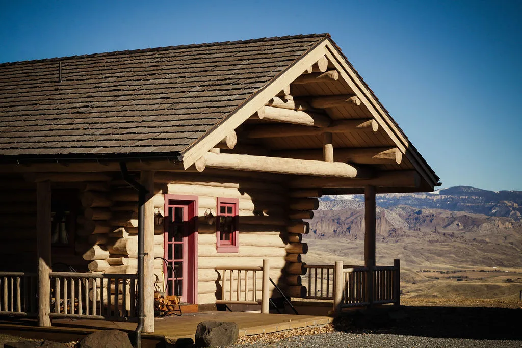 Handcrafted log cabin with covered porch and mountain backdrop