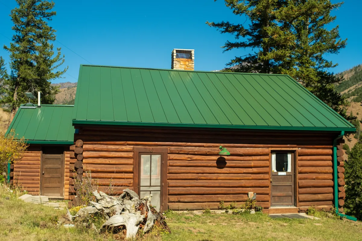 Green metal roof on mountain log cabin by Pilot Peak Construction